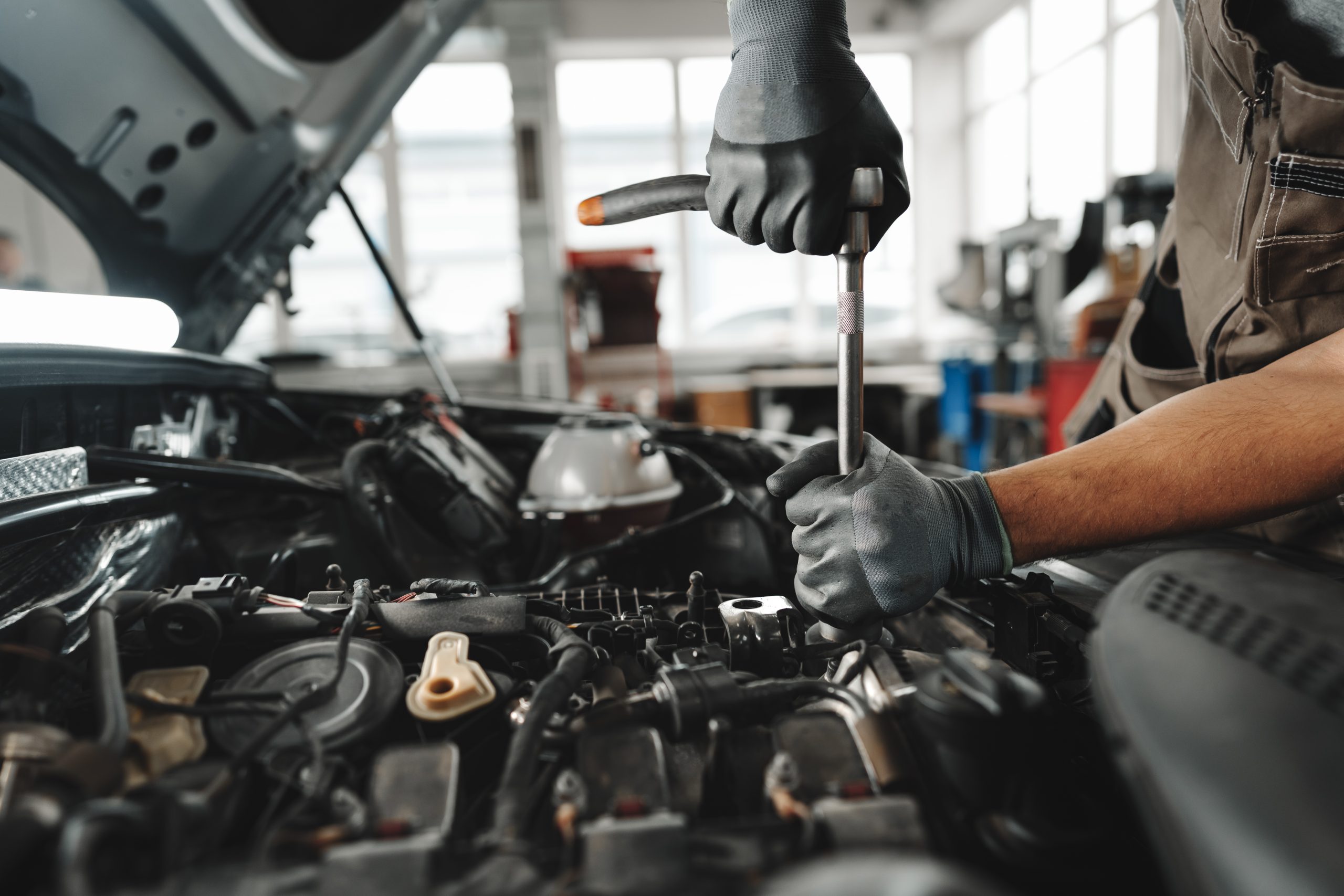 Close up of mechanic's hands repairing car engine in car service